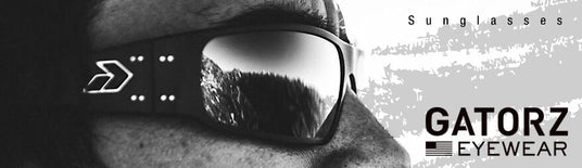 Close-up of a person wearing Gatorz sunglasses, reflecting a mountain landscape, with "Sunglasses" and "Gatorz Eyewear" text. Close-up of a person wearing Gatorz sunglasses, reflecting a mountain landscape, with "Sunglasses" and "Gatorz Eyewear" text.