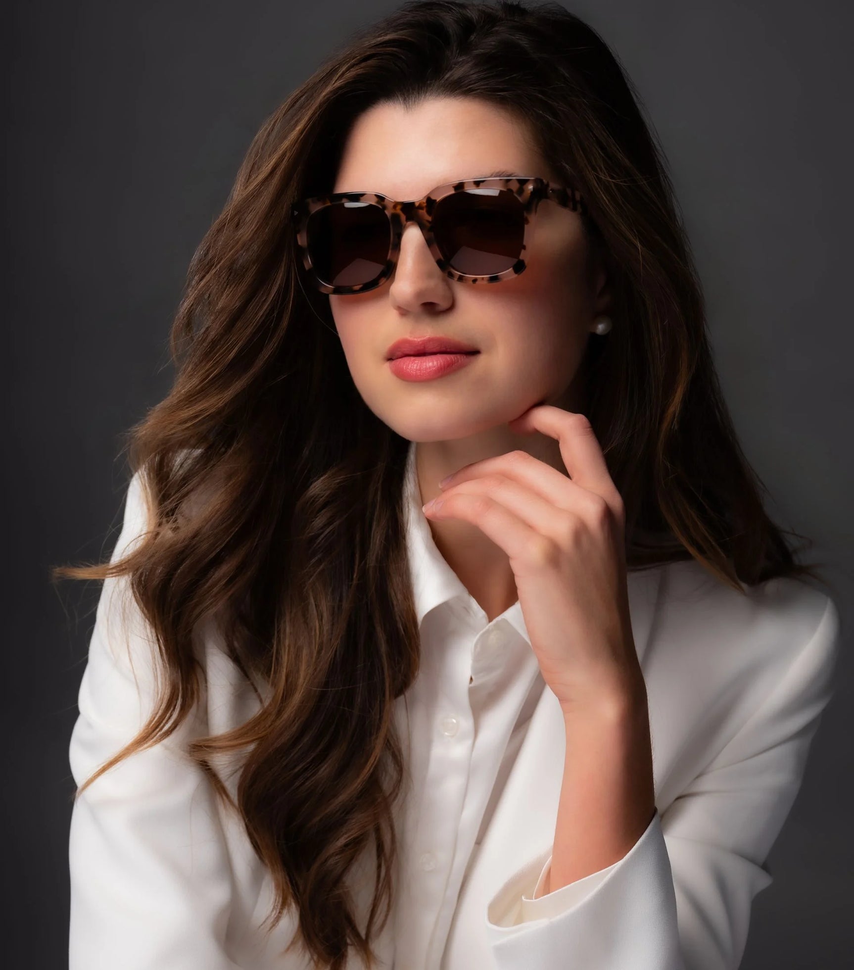 Woman with long brown hair in a white blazer wears Di Valdi DV0147 Sunglasses (Size 49) by Di Valdi, featuring polarized tortoiseshell frames with UV protection, posing against a dark background. Woman with long brown hair in a white blazer wears Di Valdi DV0147 Sunglasses (Size 49) by Di Valdi, featuring polarized tortoiseshell frames with UV protection, posing against a dark background.