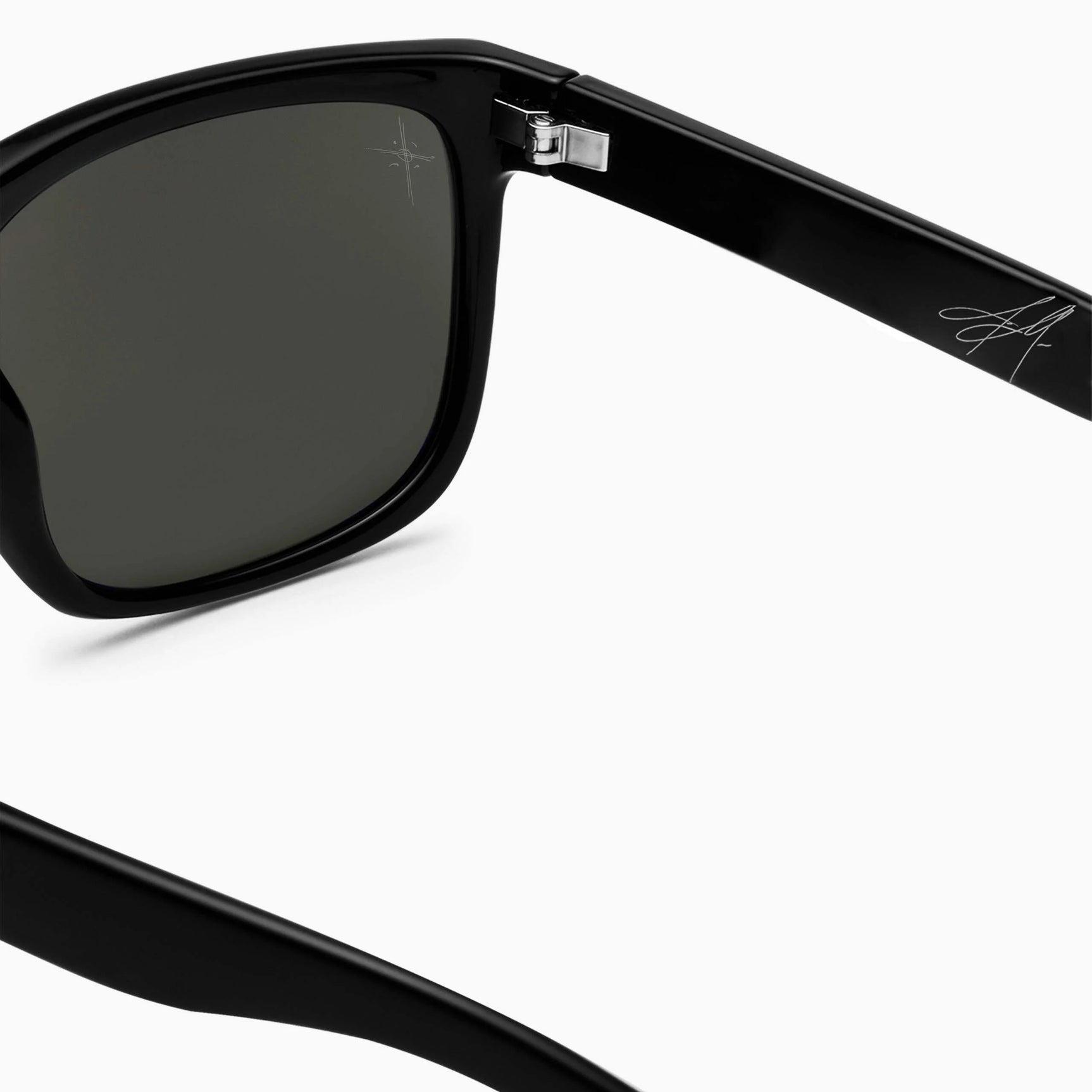 Close-up of Electric Jason Momoa Swingarm M Sunglasses with a silver hinge and signature detail on the temple, providing stylish UV protection. Close-up of Electric Jason Momoa Swingarm M Sunglasses with a silver hinge and signature detail on the temple, providing stylish UV protection.