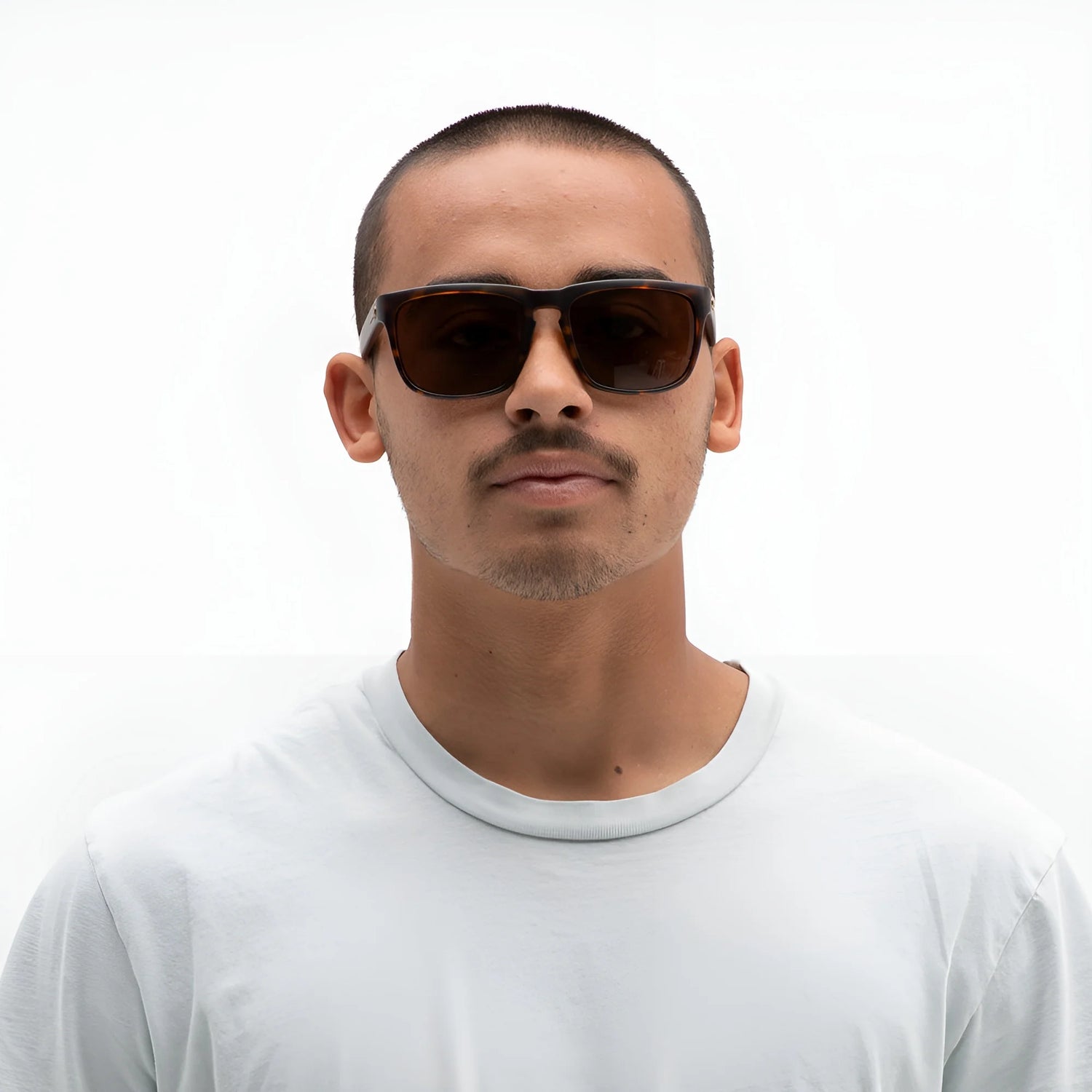 A man wearing Electric Knoxville XL Sunglasses (Size 61) by Electric and a white t-shirt stands against a plain white background, showcasing superior sun protection and a lightweight fit. A man wearing Electric Knoxville XL Sunglasses (Size 61) by Electric and a white t-shirt stands against a plain white background, showcasing superior sun protection and a lightweight fit.