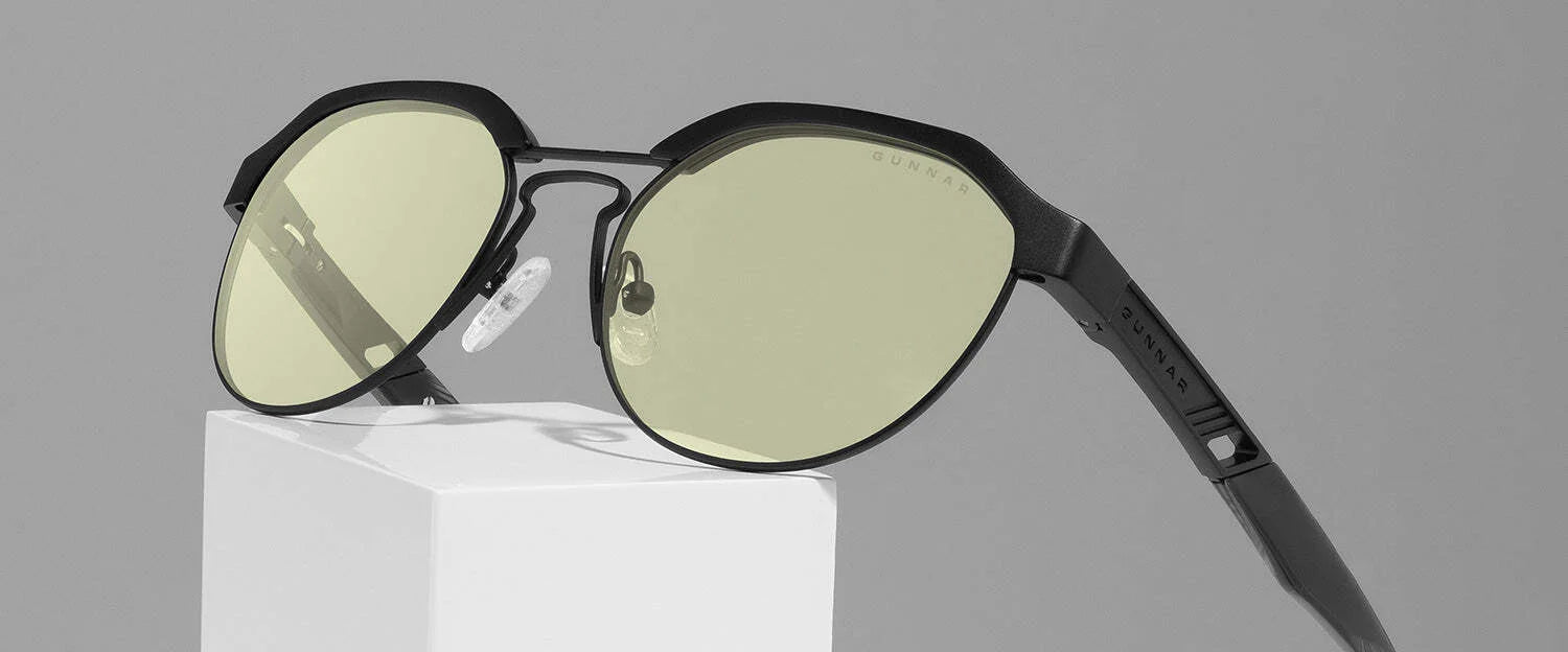 The Gunnar Campbell Computer Glasses, featuring stylish black frames and yellow-tinted blue light blocking lenses, are elegantly displayed on a white pedestal. The Gunnar Campbell Computer Glasses, featuring stylish black frames and yellow-tinted blue light blocking lenses, are elegantly displayed on a white pedestal.