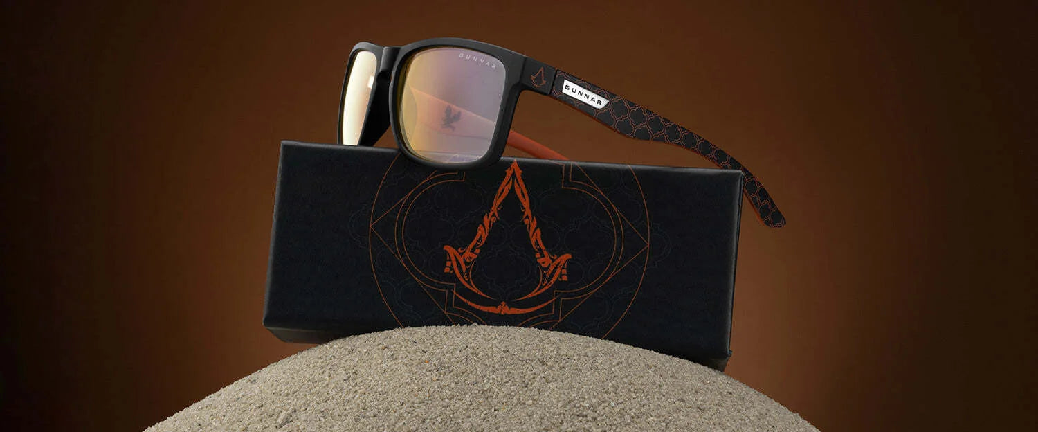 Gunnar Intercept Assassin’s Creed Mirage Edition Computer Glasses sit stylishly on a logo-emblazoned box. These licensed sunglasses, featuring red lenses, offer blue light protection and stand out against a brown gradient backdrop. Gunnar Intercept Assassin’s Creed Mirage Edition Computer Glasses sit stylishly on a logo-emblazoned box. These licensed sunglasses, featuring red lenses, offer blue light protection and stand out against a brown gradient backdrop.