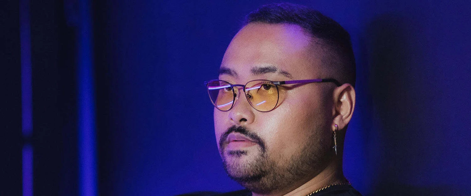 A bearded person with glasses looks sideways, wearing Gunnar Mateo Black Panther Vibranium Edition Computer Glasses with patented lens technology. The light titanium frame stands out against the dark blue background. A bearded person with glasses looks sideways, wearing Gunnar Mateo Black Panther Vibranium Edition Computer Glasses with patented lens technology. The light titanium frame stands out against the dark blue background.