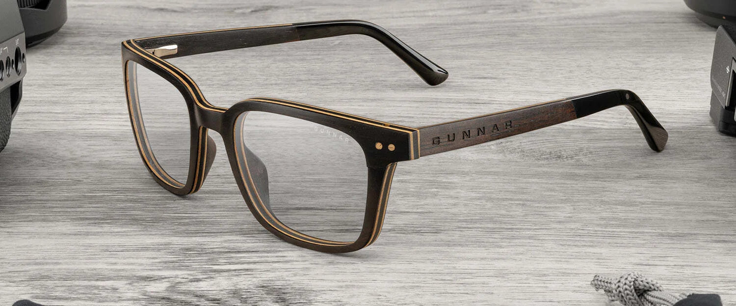 Rectangular glasses with a dark, textured wooden frame from sustainably harvested ebony, part of the AROBR Collection. The Gunnar Muir Computer Glasses | Size 50 feature "Gunnar" branding on the arm and rest elegantly on a gray surface. Rectangular glasses with a dark, textured wooden frame from sustainably harvested ebony, part of the AROBR Collection. The Gunnar Muir Computer Glasses | Size 50 feature "Gunnar" branding on the arm and rest elegantly on a gray surface.