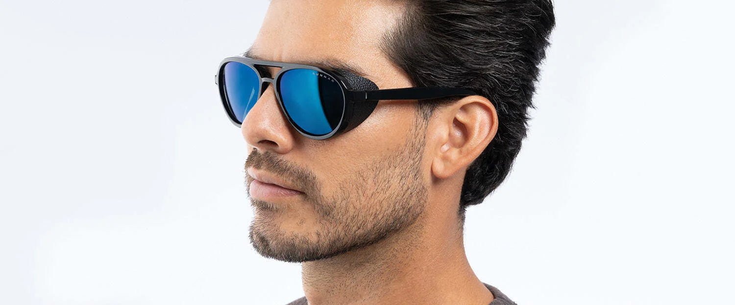 A bearded man with short hair wears reflective blue Gunnar Tallac Sunglasses, Size 57, as he looks to the side. A bearded man with short hair wears reflective blue Gunnar Tallac Sunglasses, Size 57, as he looks to the side.