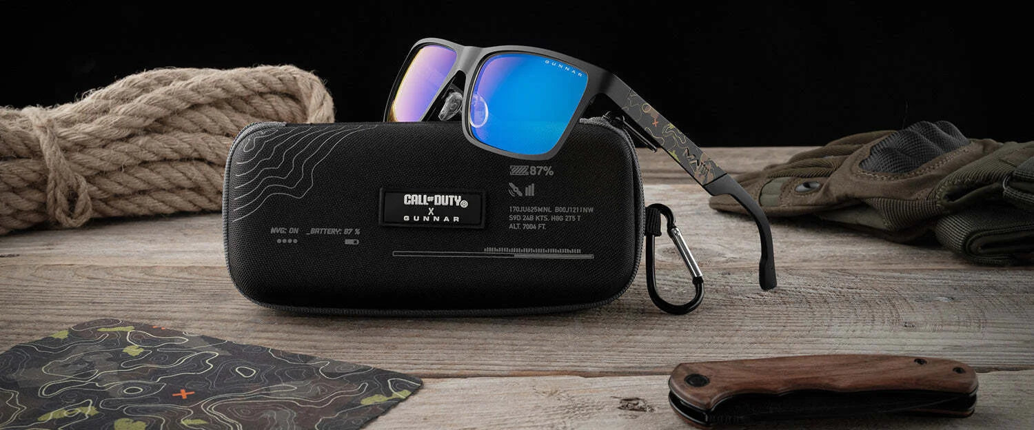 Gunnar Call of Duty UAV Edition Computer Glasses, featuring an aluminum-magnesium forged frame, rest on a case with gloves, a knife, and a map on the wooden surface. Gunnar Call of Duty UAV Edition Computer Glasses, featuring an aluminum-magnesium forged frame, rest on a case with gloves, a knife, and a map on the wooden surface.