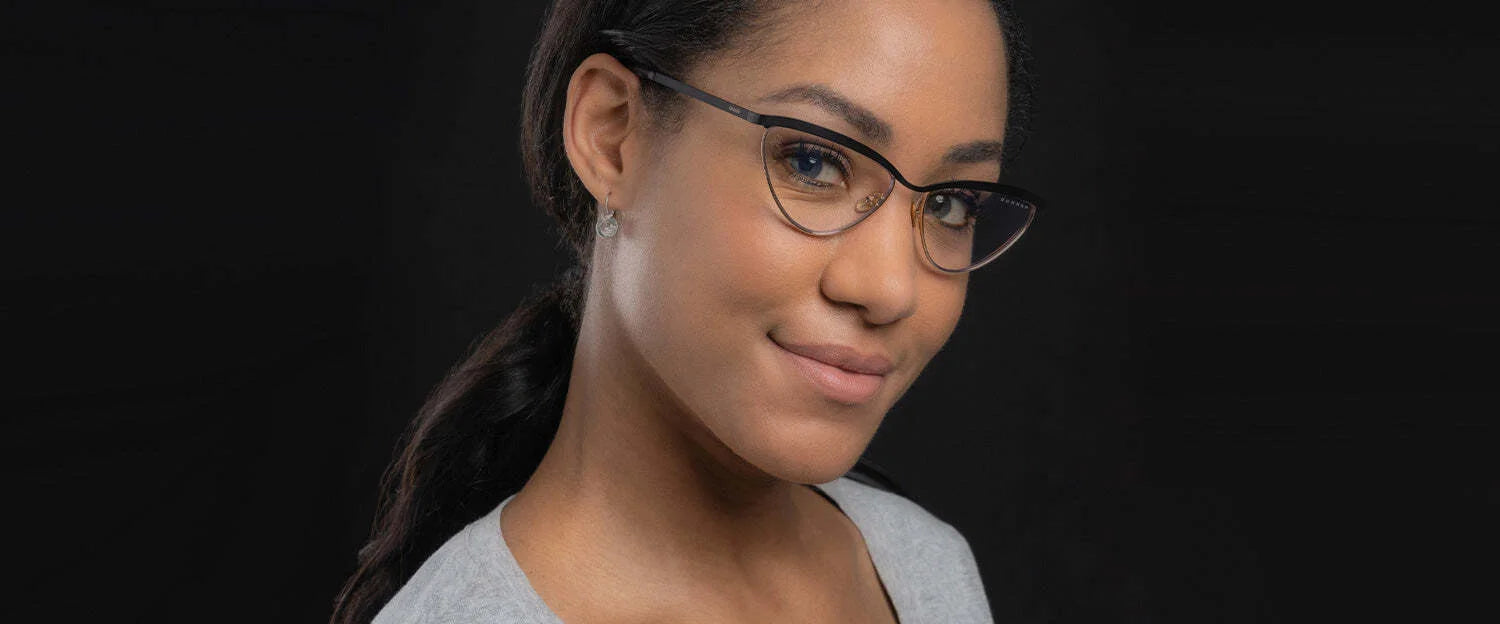 Smiling softly in a gray top against a black background, a person wears Gunnar Tokidoki Year of the Dragon Computer Glasses, featuring a delicate Chinese dragon pattern. Smiling softly in a gray top against a black background, a person wears Gunnar Tokidoki Year of the Dragon Computer Glasses, featuring a delicate Chinese dragon pattern.