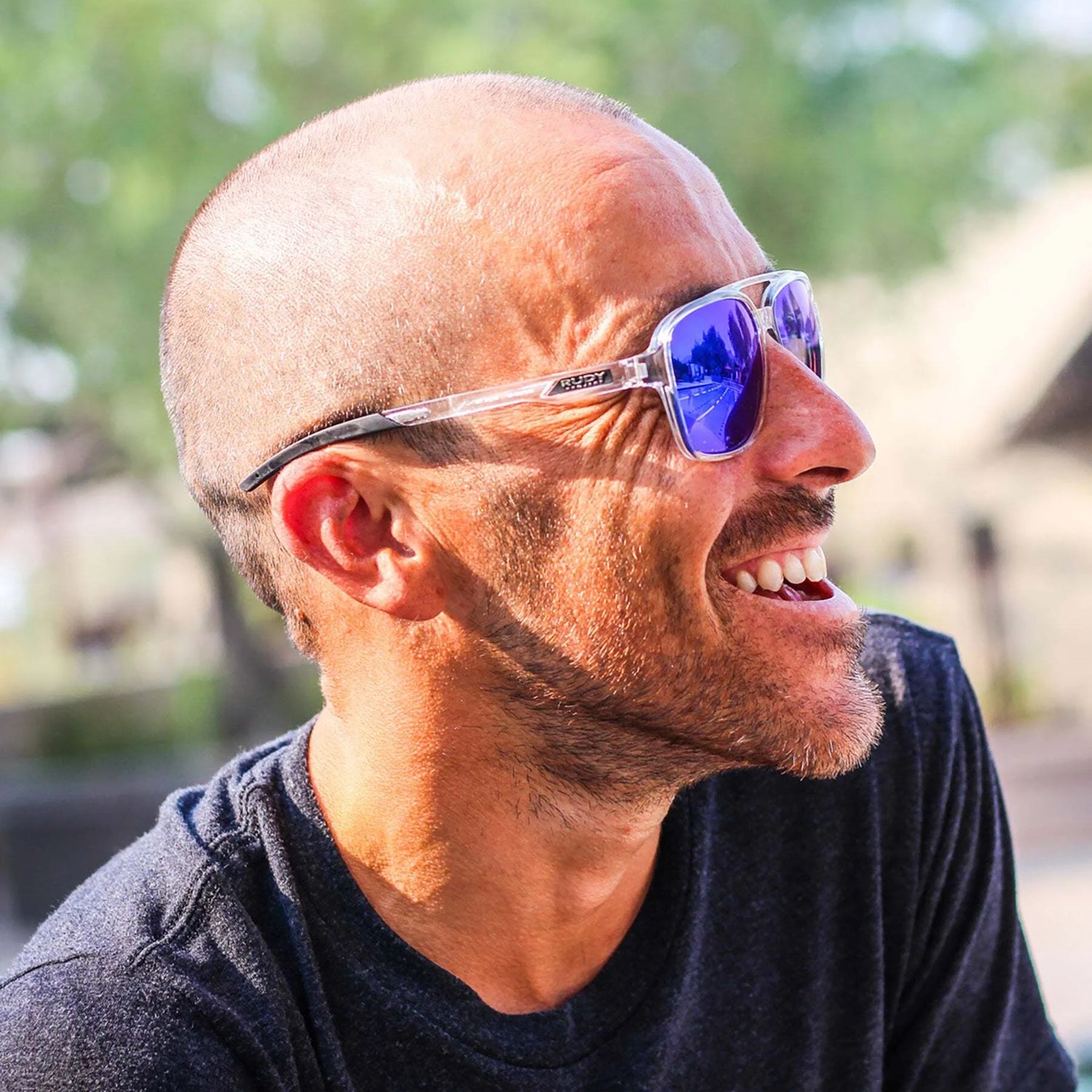 Bearded man in a dark shirt outdoors, wearing Rudy Project Croze Sunglasses (Size 57) with UV protection by Rudy Project. Bearded man in a dark shirt outdoors, wearing Rudy Project Croze Sunglasses (Size 57) with UV protection by Rudy Project.