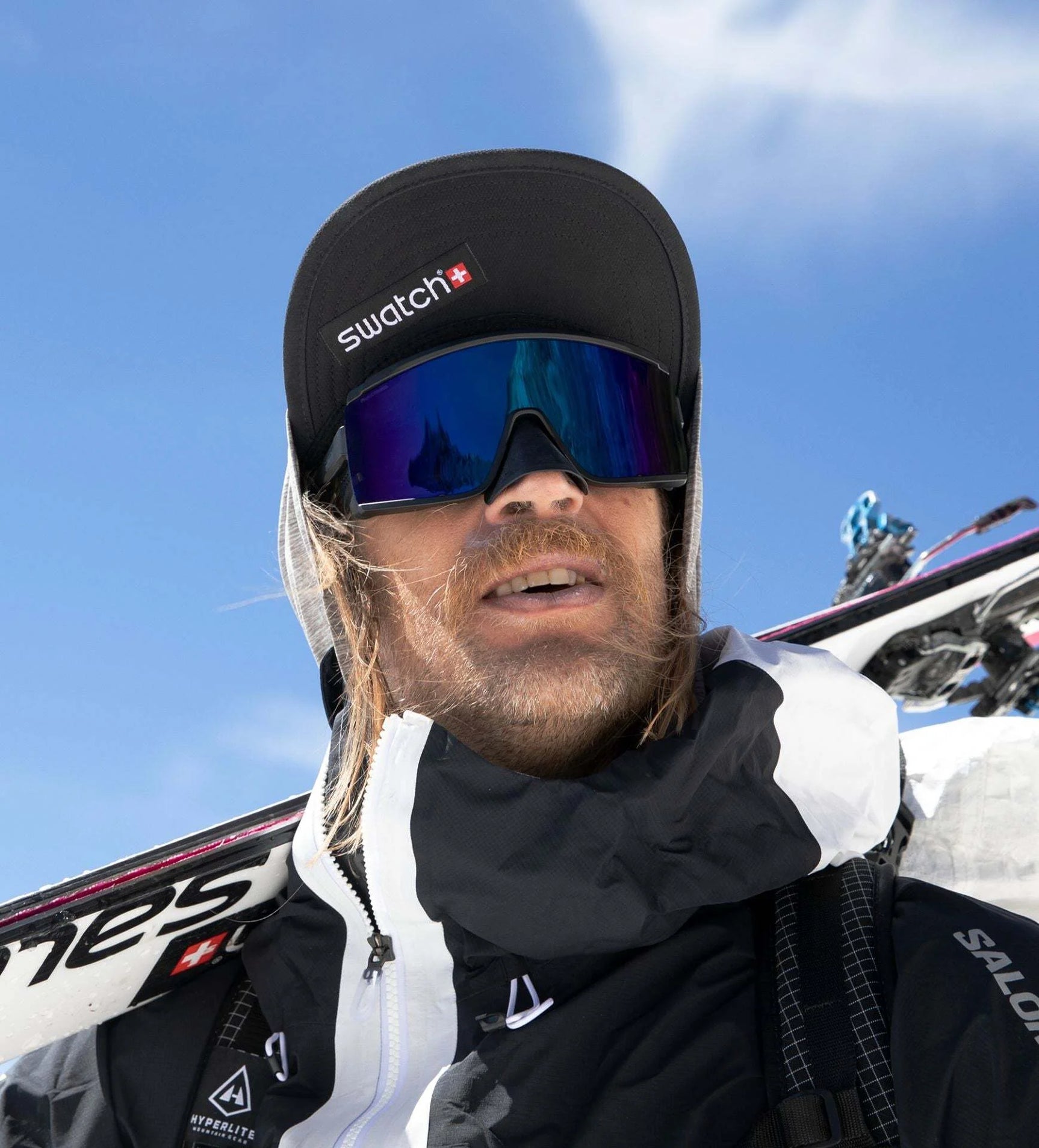 A person in a black cap and ski gear with skis on their shoulder stands against a blue sky, sporting the sleek Smith Optics Pursuit Sunglasses for optimal vision. A person in a black cap and ski gear with skis on their shoulder stands against a blue sky, sporting the sleek Smith Optics Pursuit Sunglasses for optimal vision.