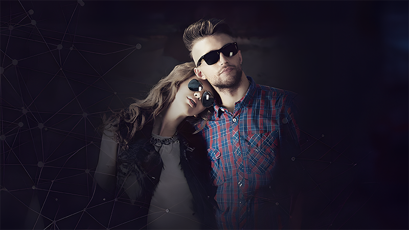 A couple in sunglasses poses in stylish attire against a dark, abstract background.