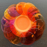 RE Ranger Spare Prescription Lenses by RE Ranger, featuring orange-tinted anti-reflective lenses, are arranged in a circle around a White Flyer clay target.