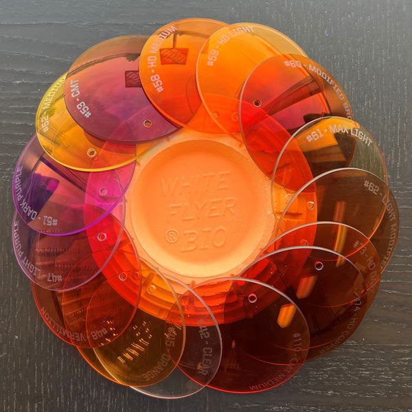RE Ranger Spare Prescription Lenses by RE Ranger, featuring orange-tinted anti-reflective lenses, are arranged in a circle around a White Flyer clay target.