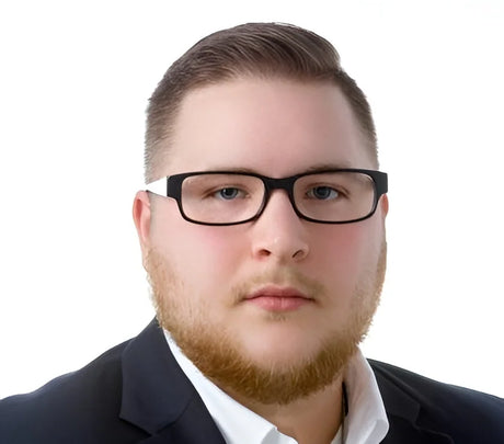 A man with a beard and a suit faces the camera against a plain white background, wearing bold black Fatheadz JAXSONIAN Eyeglasses, Size 60.