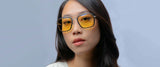 A person wearing Gunnar Barron Computer Glasses with yellow-tinted lenses and a white sweater against a light gray background.