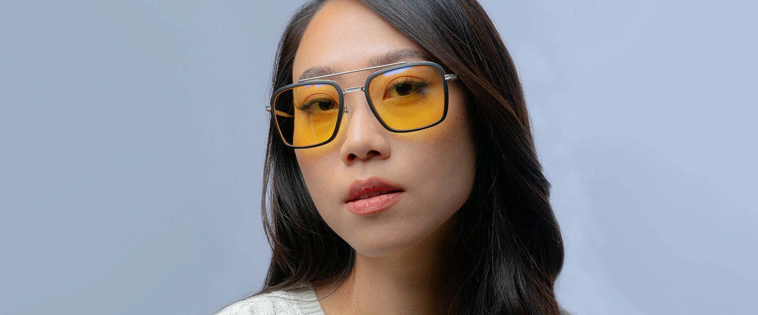 A person wearing Gunnar Barron Computer Glasses with yellow-tinted lenses and a white sweater against a light gray background.