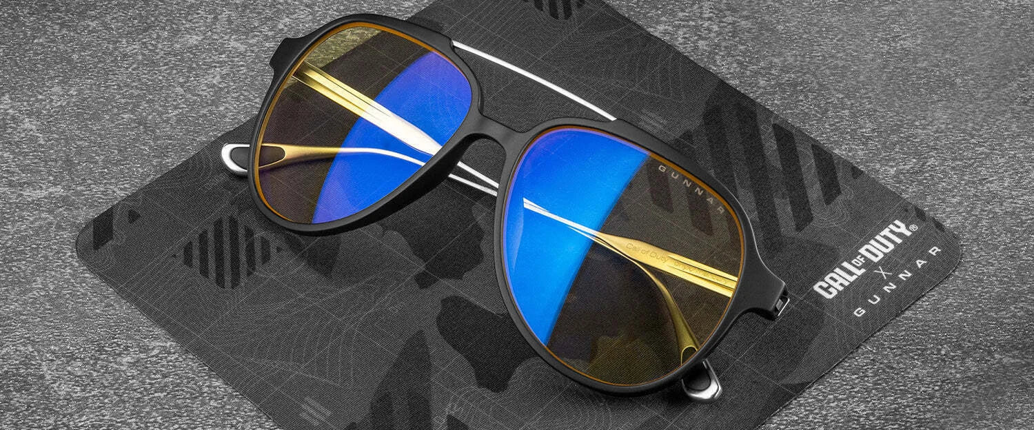 Gunnar Call of Duty Ghost Edition Computer Glasses, with sleek black frames and blue-tinted lenses, rest stylishly on a themed case on a gray surface. A perfect blend of gaming and fashion for enthusiasts.