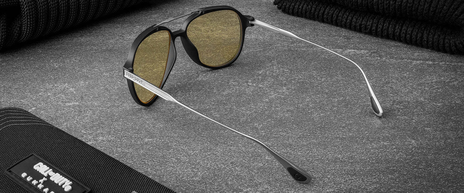 Black and gold Gunnar Call of Duty Ghost Edition Computer Glasses with photochromic Amber lenses rest elegantly on a dark textured surface, accompanied by a sleek black case.