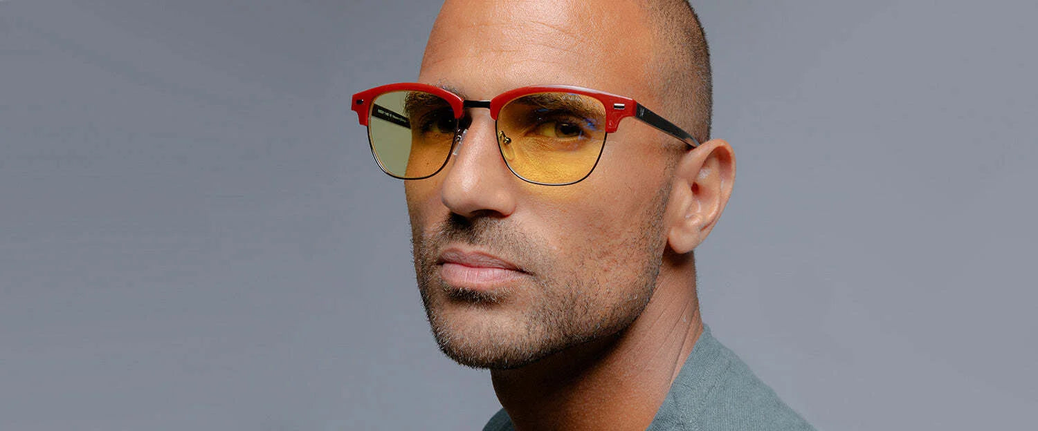 A man with short hair wears distinctive Gunnar Diablo IV Sanctuary Edition Computer Glasses in red and yellow, set against a plain background.