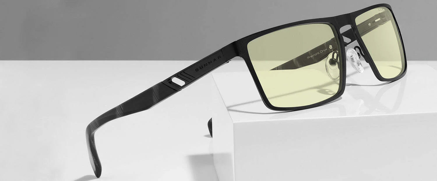 The Gunnar Fremont Computer Glasses, size 59, with sleek black rims and yellow-tinted lenses, elegantly rest on a white surface. Designed for blue light blocking, they provide comfort and style during extended screen time.