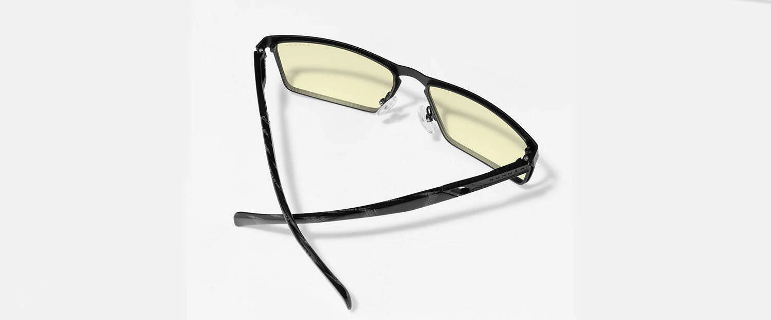 The Gunnar Fremont Computer Glasses | Size 59 boast black-rimmed, yellow-tinted lenses designed to block blue light. Their sleek mix of stainless steel and acetate adds a modern touch on a light backdrop.