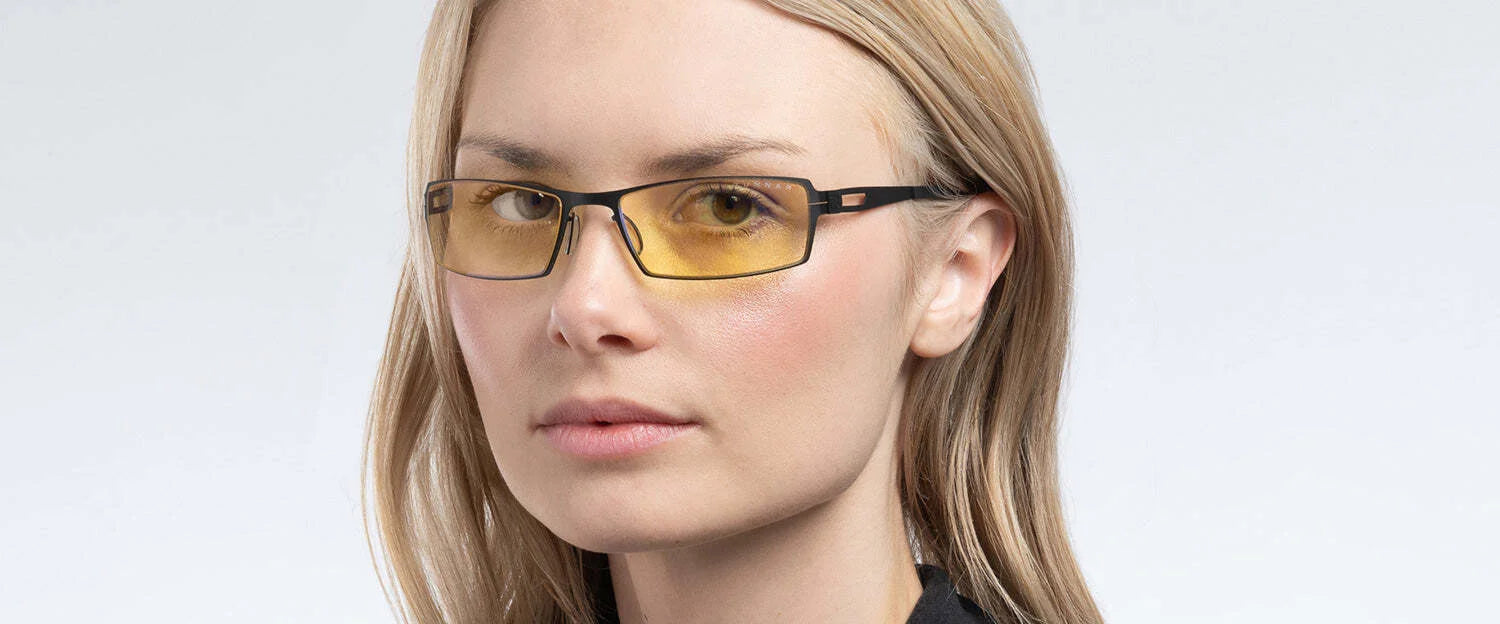 A person wearing Gunnar Sheadog Computer Glasses (Size 56) with GUNNAR lens material and yellow-tinted, blue light blocking lenses is dressed in a black top against a neutral background.