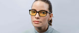 A person in a gray shirt wears Gunnar Haus Reading Computer Glasses, Size 53. Crafted from European materials, these yellow-tinted glasses provide style and effective blue light blocking against a plain background.