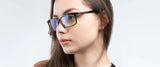 A person with long brown hair wears Gunnar Haus Reading Computer Glasses, Size 53, with black frames and a reflective yellow tint. Crafted from European materials, these stylish glasses feature blue light blocking technology for comfort.