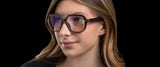 Against a black backdrop, a woman wears Gunnar Humboldt Computer Glasses in Size 54. Their oversized brown frames come with Gunnar lens technology for improved clarity and comfort.
