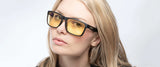 A blonde-haired individual wears Gunnar Intercept Computer Glasses, Size 58, with black frames and yellow lenses for blue light protection, glancing slightly to the side.