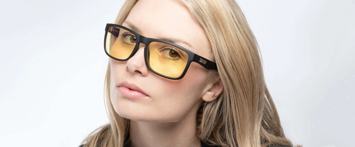 A person with long blond hair wears Gunnar Intercept Reading Computer Glasses, size 58, in black and yellow against a light gray background. These stylish glasses offer blue light protection with a durable nylon frame.