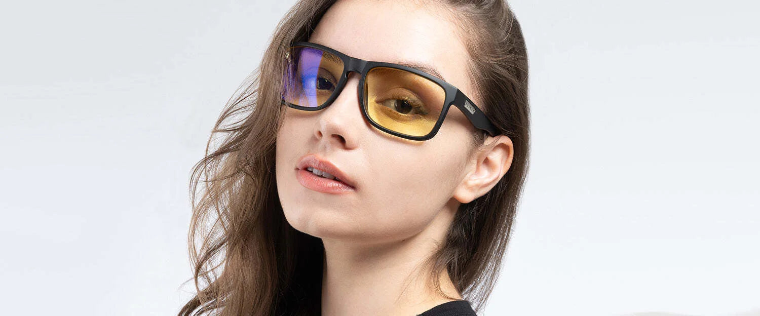 A person is wearing Gunnar Intercept Reading Computer Glasses, featuring one blue-tinted and one yellow-tinted lens, set against a plain background. The durable nylon frame suggests the stylish design offers blue light protection with every glance.