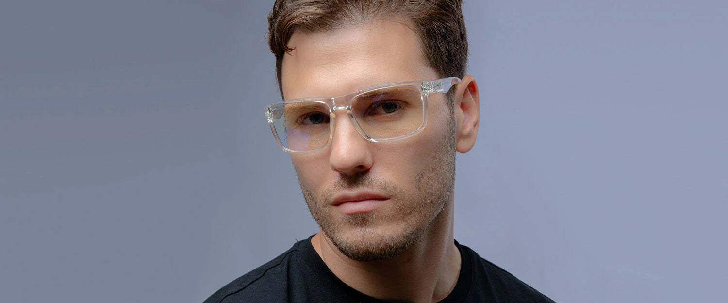 A person wearing Gunnar Intercept Computer Glasses featuring clear frames with blue light protection and a black shirt gazes toward the camera against a gray background.