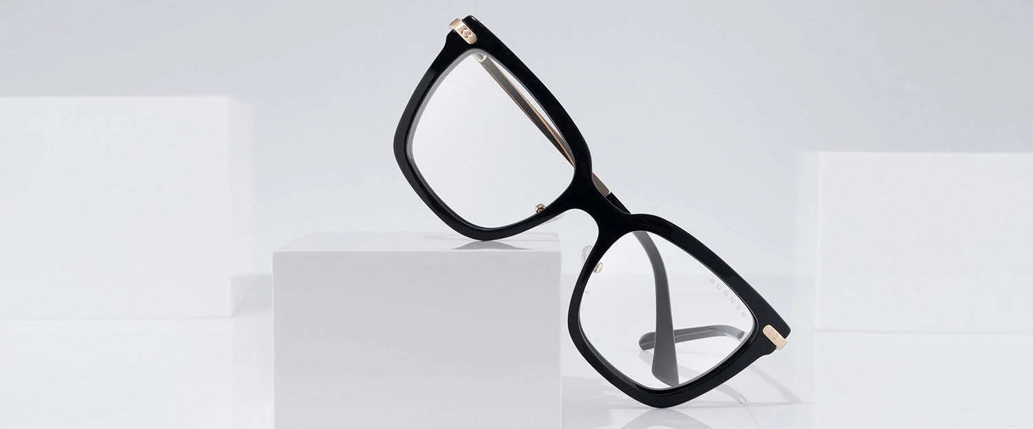 The Gunnar Kaia Computer Glasses, size 53, elegantly feature a black square design with gold accents and innovative blue light blocking technology, showcased on sleek white geometric blocks.