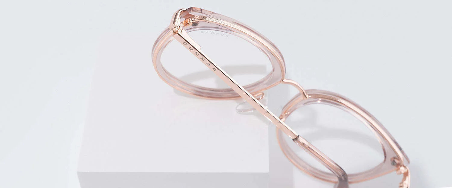 Gunnar Lahti Computer Glasses in rose-gold are elegantly displayed on white blocks, highlighting their chic side profile. Featuring GUNNAR lens technology, these designer glasses combine style with blue light protection for the modern individual.