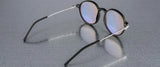 Gunnar Loop Computer Glasses, featuring black frames and thin silver arms, reflect light on a textured gray surface. Enhanced with GUNNAR lens technology for optimal productivity.