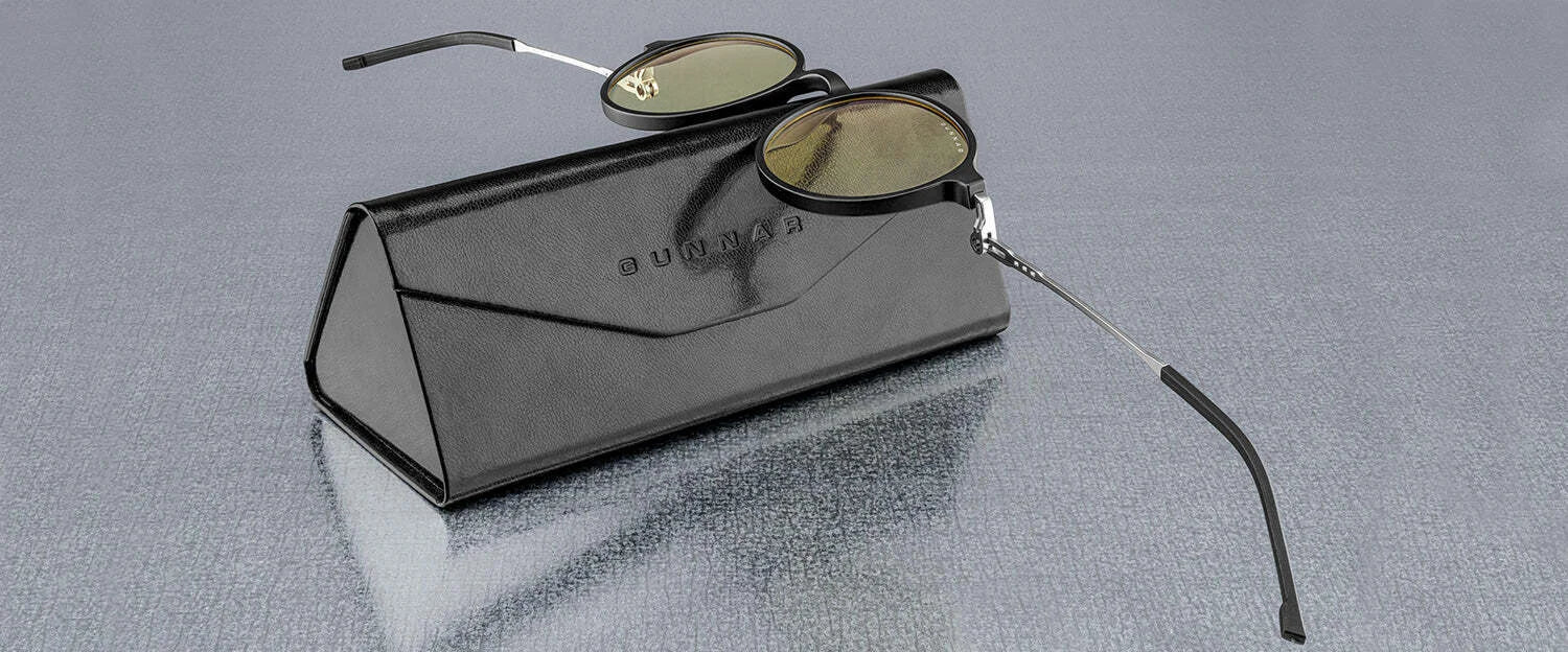 The Gunnar Loop Computer Glasses, with round lenses and advanced lens technology for better productivity, are placed on a black leather case atop a reflective surface.