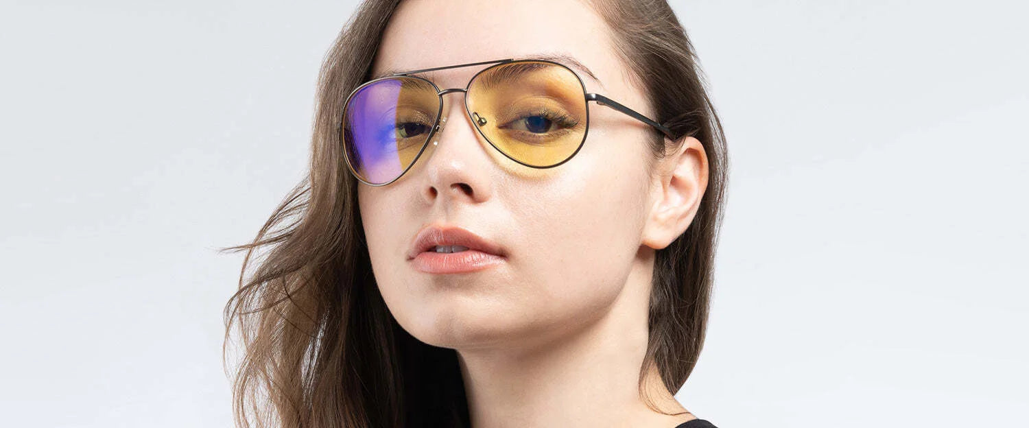 A person wearing Gunnar Maverick Computer Glasses with yellow-tinted lenses for blue light protection and an anti-reflective finish maintains a neutral expression against a light background.