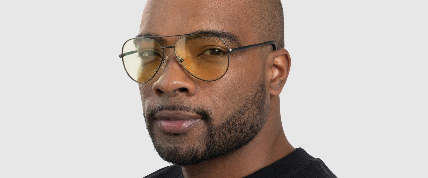 A man in a black sweater poses against a plain white background wearing Gunnar Maverick Computer Glasses | Size 58 with tinted lenses.