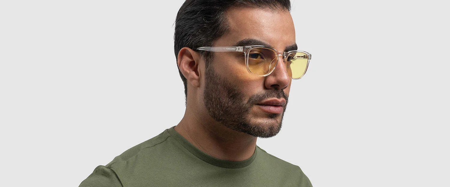 A man in a green shirt wears Gunnar Oakland Computer Glasses, Size 53, featuring yellow-tinted lenses and a durable nylon frame, offering blue light protection while gazing to the side.