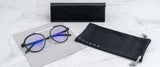 Gunnar Pacifica Computer Glasses | Size 50 have round, blue-tinted, blue light blocking lenses and are paired with a sleek black case and drawstring pouch, elegantly displayed on a marble surface.