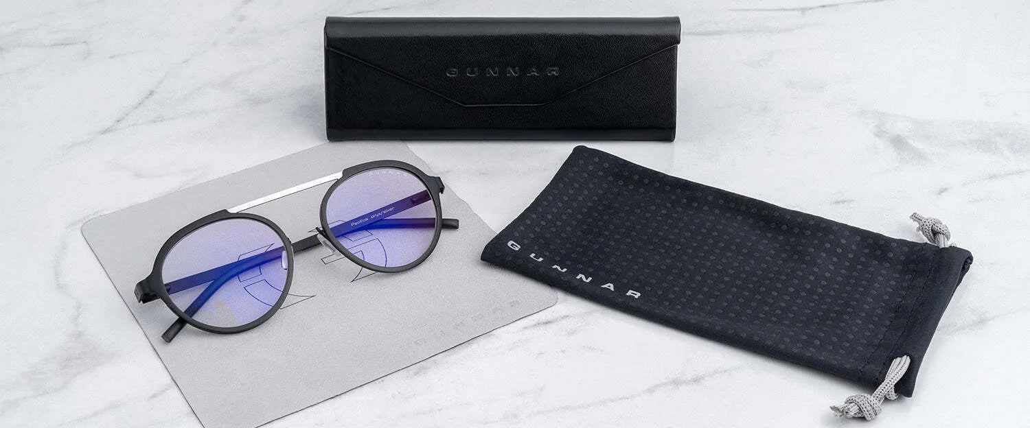 Gunnar Pacifica Computer Glasses | Size 50 have round, blue-tinted, blue light blocking lenses and are paired with a sleek black case and drawstring pouch, elegantly displayed on a marble surface.