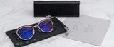 Gunnar's Palomar Computer Glasses with blue lenses, echoing a round glasses style, are placed on a pouch next to a cleaning cloth and case on a marble surface.