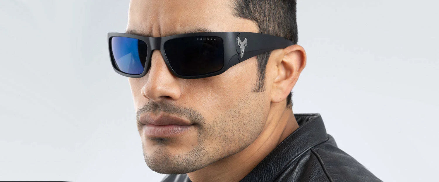 Person wearing fashionable Gunnar Overwatch Reaper Sunglasses, Size 58, with a leather jacket, looking to the side against a gray background.