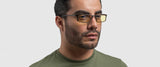 A man in a green shirt wears Gunnar Phenom Reading Computer Glasses (Size 55), showcasing advanced optical technology, against a light gray background.