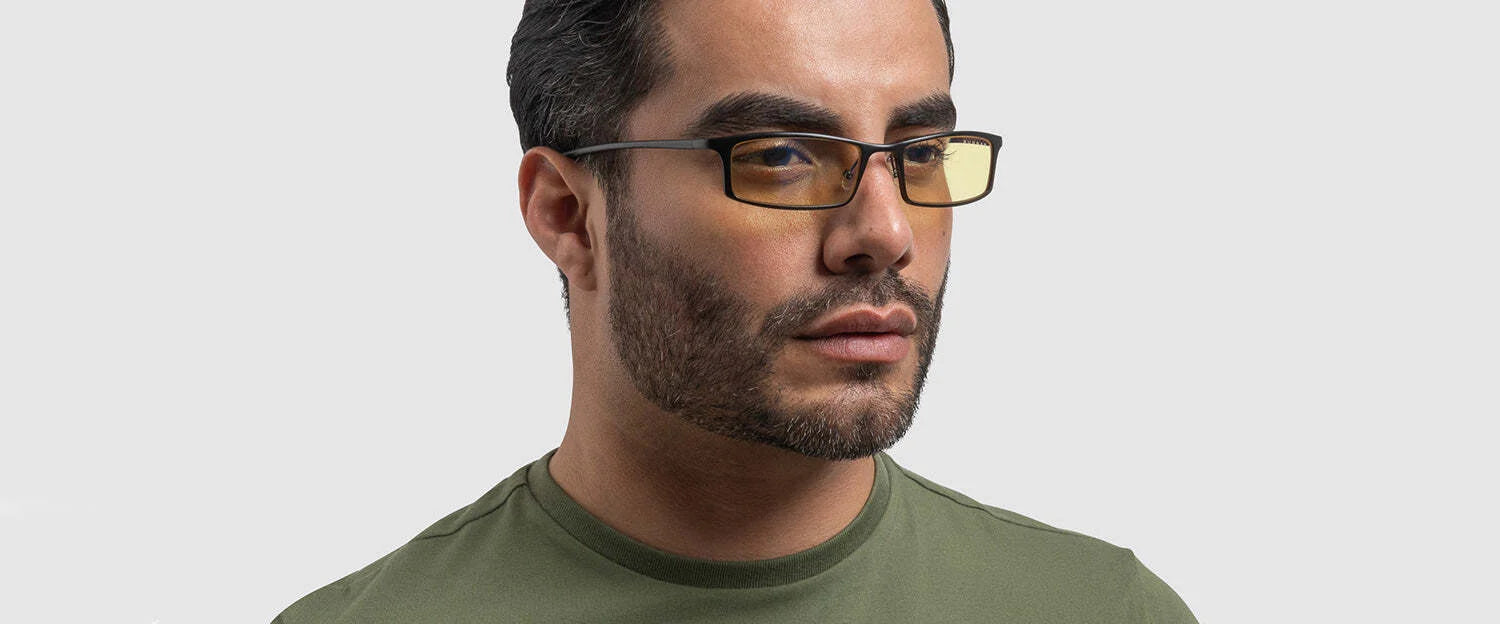 A man in a green shirt wears Gunnar Phenom Reading Computer Glasses (Size 55), showcasing advanced optical technology, against a light gray background.