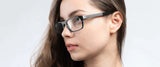 A person with long hair, wearing Gunnar Tahoe Computer Glasses Size 55, featuring mineral glass lenses, gazes to the side against a plain background.