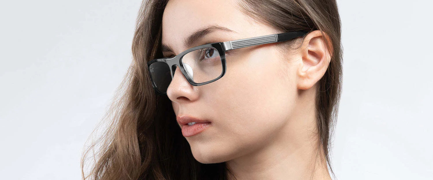 A person with long hair, wearing Gunnar Tahoe Computer Glasses Size 55, featuring mineral glass lenses, gazes to the side against a plain background.