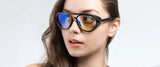 A woman wears Gunnar Tallac Computer Glasses by Gunnar in a mountaineer style, featuring one gold and one blue mirrored lens crafted from premium acetate, as she gazes to the side with a neutral expression.