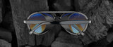 The Gunnar Tallac Computer Glasses in size 57, featuring a premium acetate frame and blue reflective lenses, combine rugged durability with sleek elegance on a dark textured background.