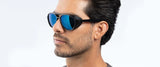 A bearded man with short hair wears reflective blue Gunnar Tallac Sunglasses, Size 57, as he looks to the side.